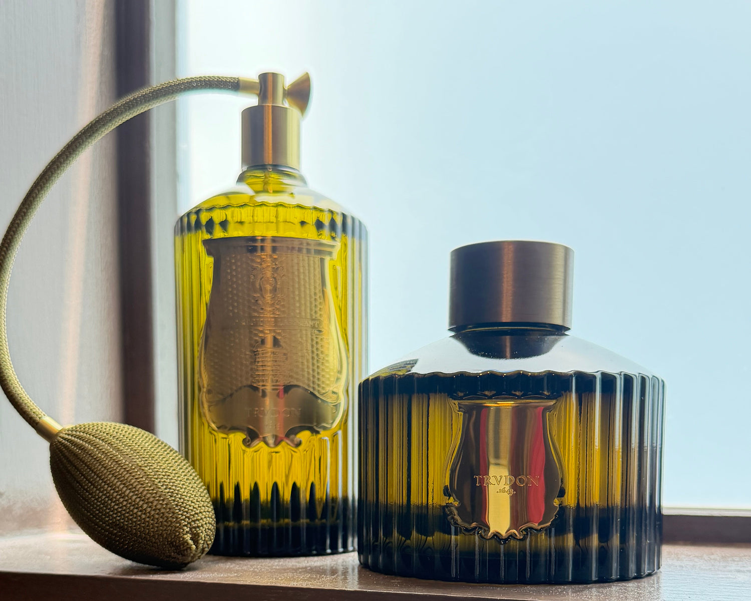 Two yellow perfume bottles with gold caps on a wooden surface.