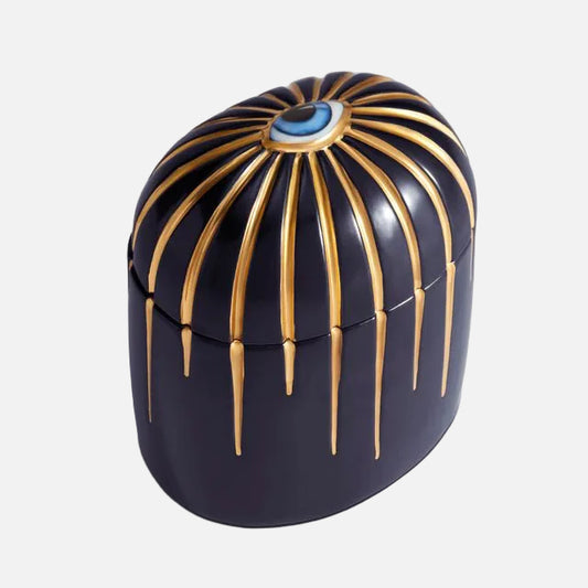 Decorative candle with gold accents and a blue gemstone on a white background