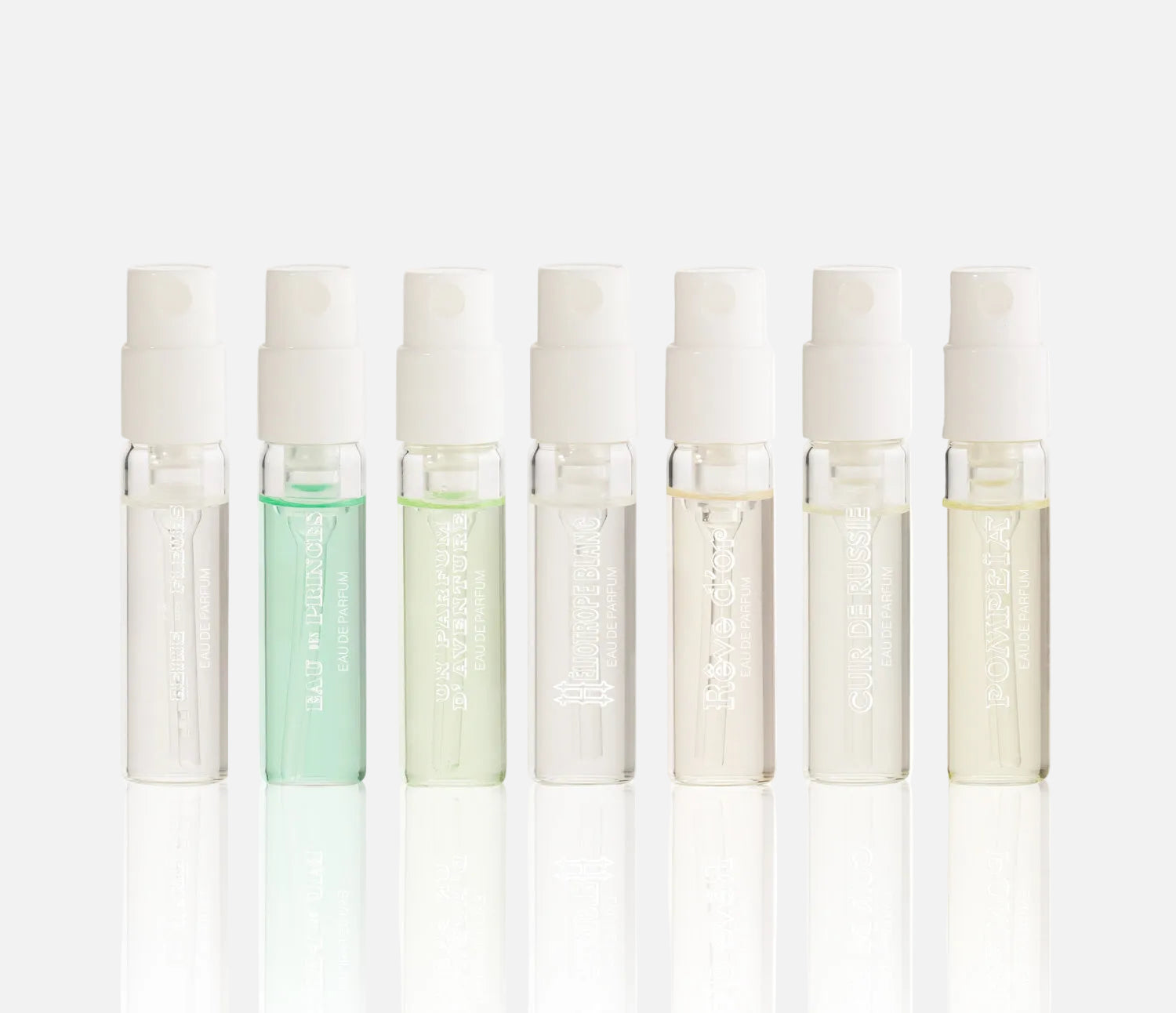Set of eight small glass bottles with white caps on a white background
