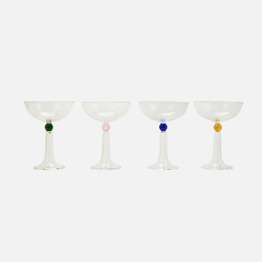 Four cocktail glasses with colored beads on a light gray background