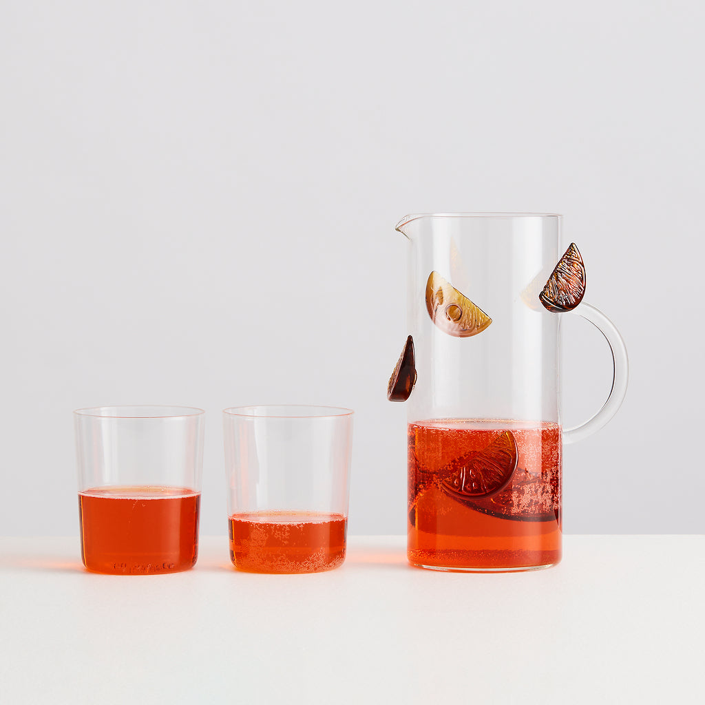 Glass pitcher and two glasses filled with a red liquid on a white background
