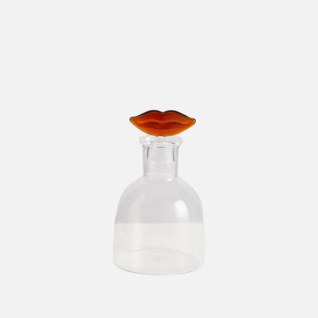 Clear glass decanter with a amber-colored stopper on a white background