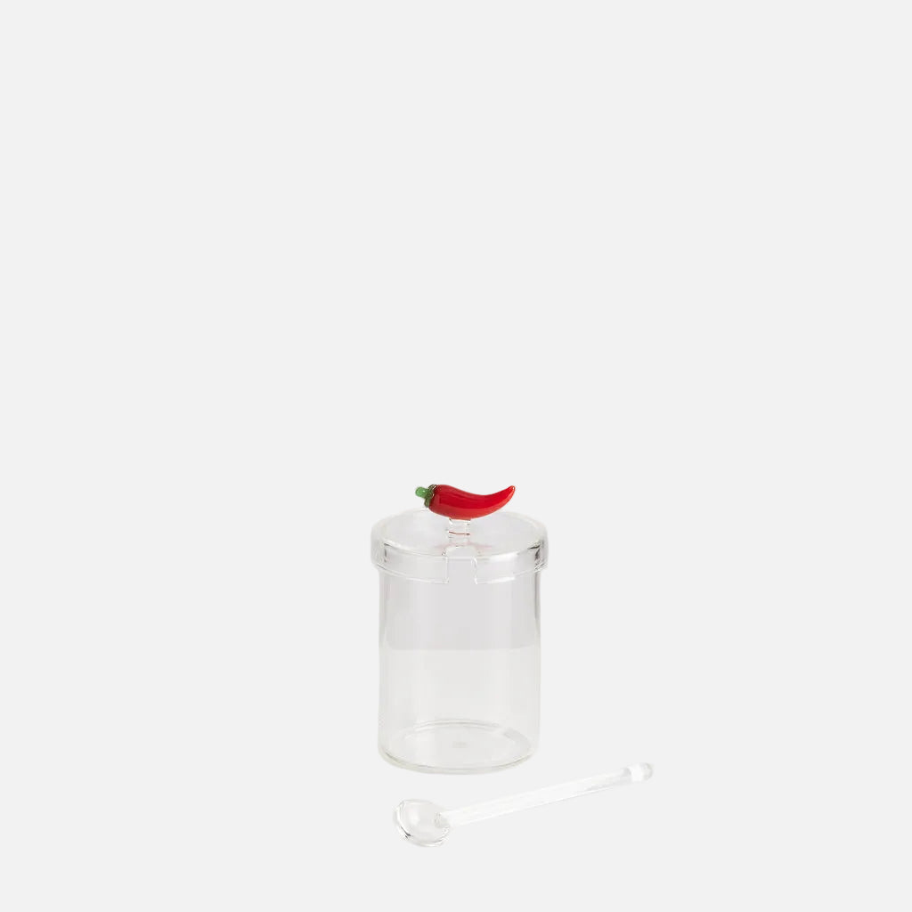 Clear glass pepper grinder with a red pepper on a white background