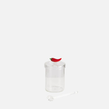 Clear glass pepper grinder with a red pepper on a white background