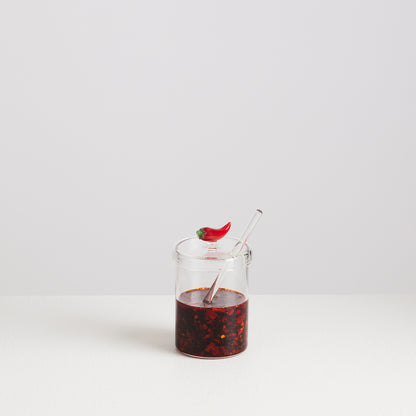 Glass jar with red liquid and a straw on a white background