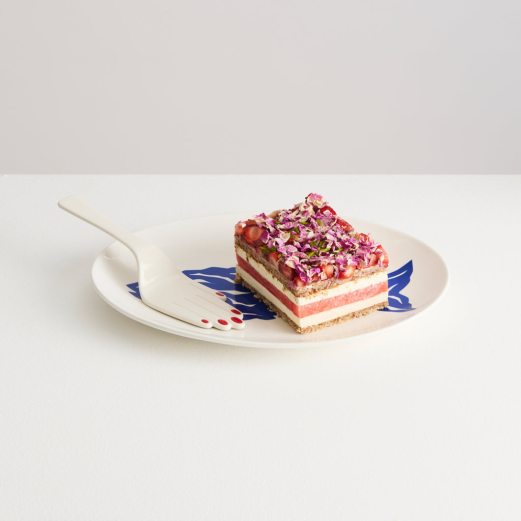 Sliced layered dessert on a decorative plate with a white background