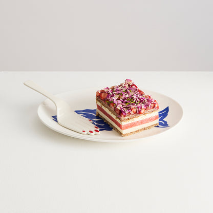 Sliced layered dessert on a decorative plate with a white background