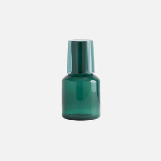 Green glass bottle with a metallic cap on a light gray background