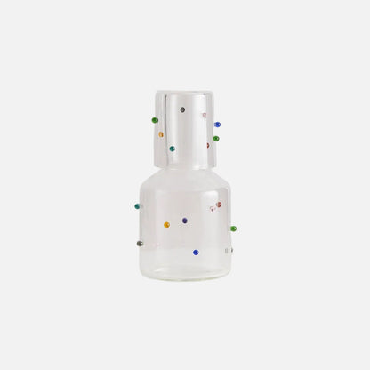 Clear glass bottle with colorful dots on a light gray background
