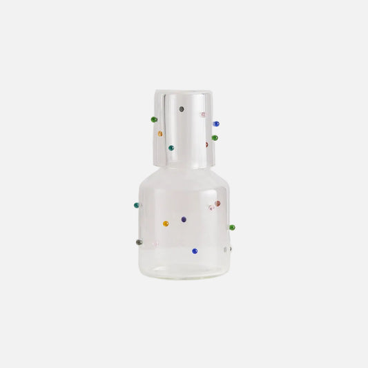 Clear glass bottle with colorful dots on a light gray background