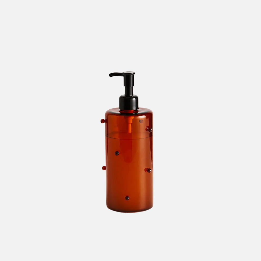 Amber glass bottle with black pump on a light gray background