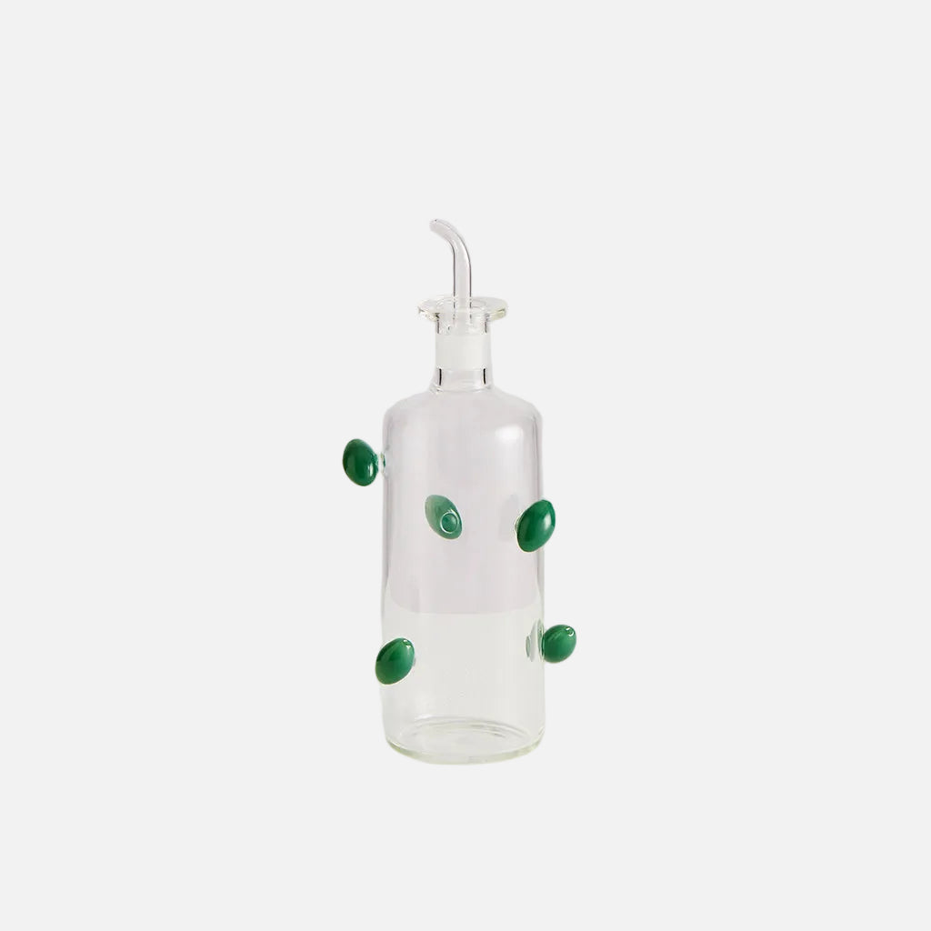 Clear glass bottle with green decorative elements on a white background