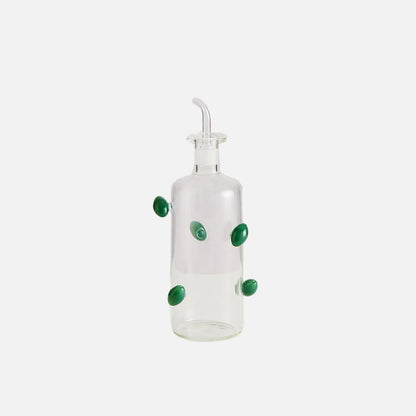 Clear glass bottle with green decorative elements on a white background