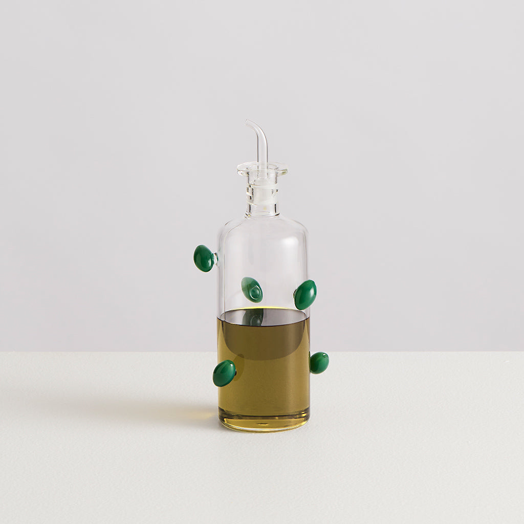 Glass oil dispenser with green accents on a white background