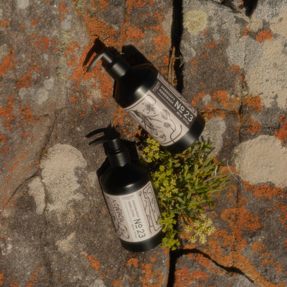 Two black bottles with labels on a textured stone surface