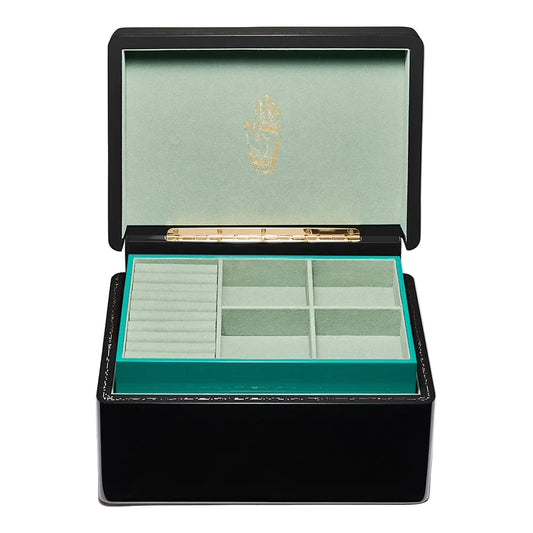 A black lacquered jewelry box with its lid open, showing a mint green velvet interior with a gold crest on the inside lid and multiple compartments.