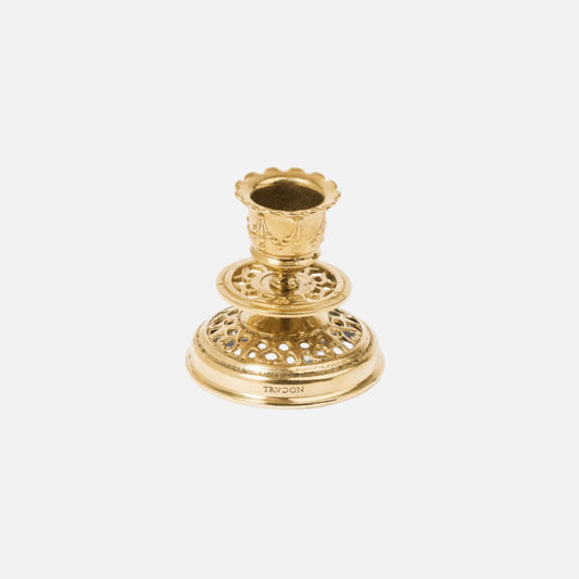 Gold candle holder with intricate design on a white background