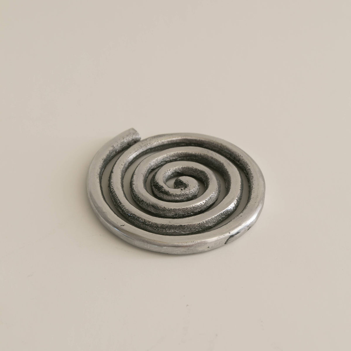 Metallic spiral object on a beige background