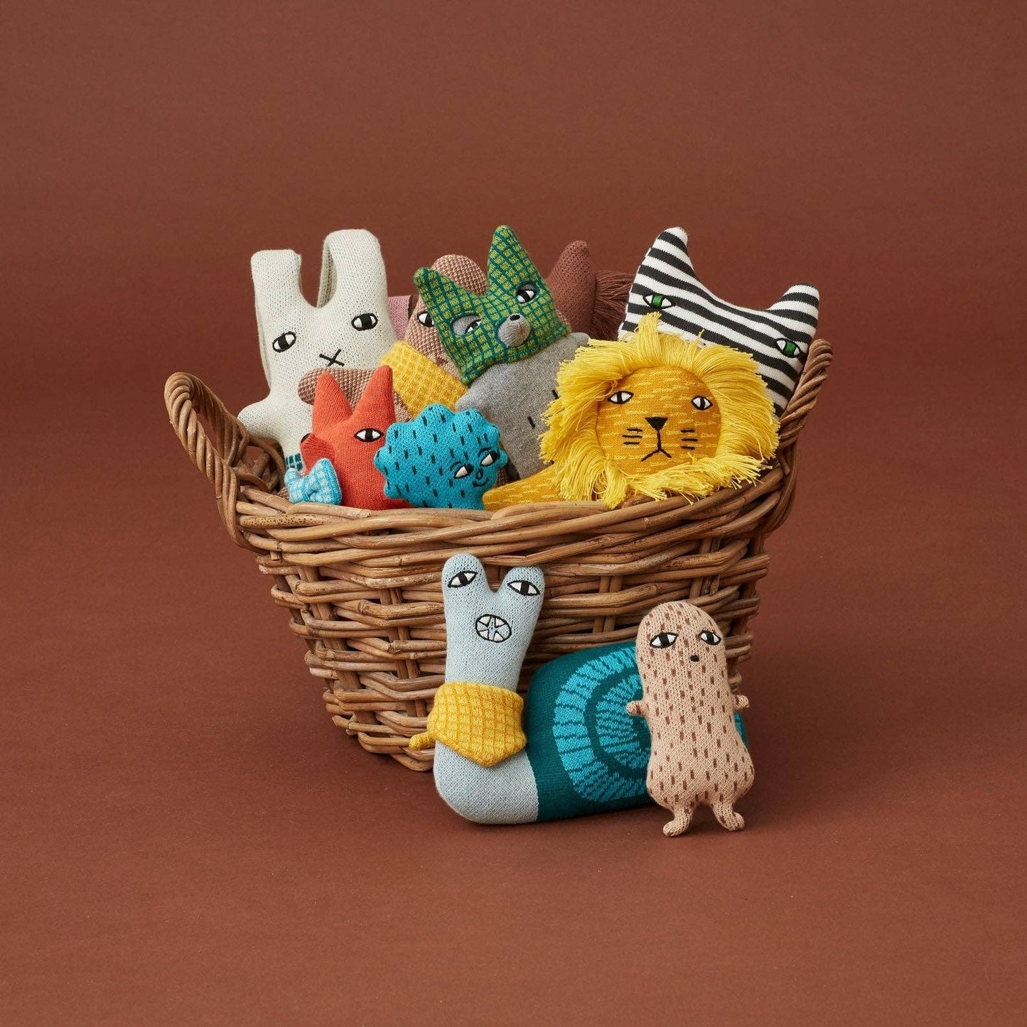 Wicker basket filled with colorful soft toys on a brown background