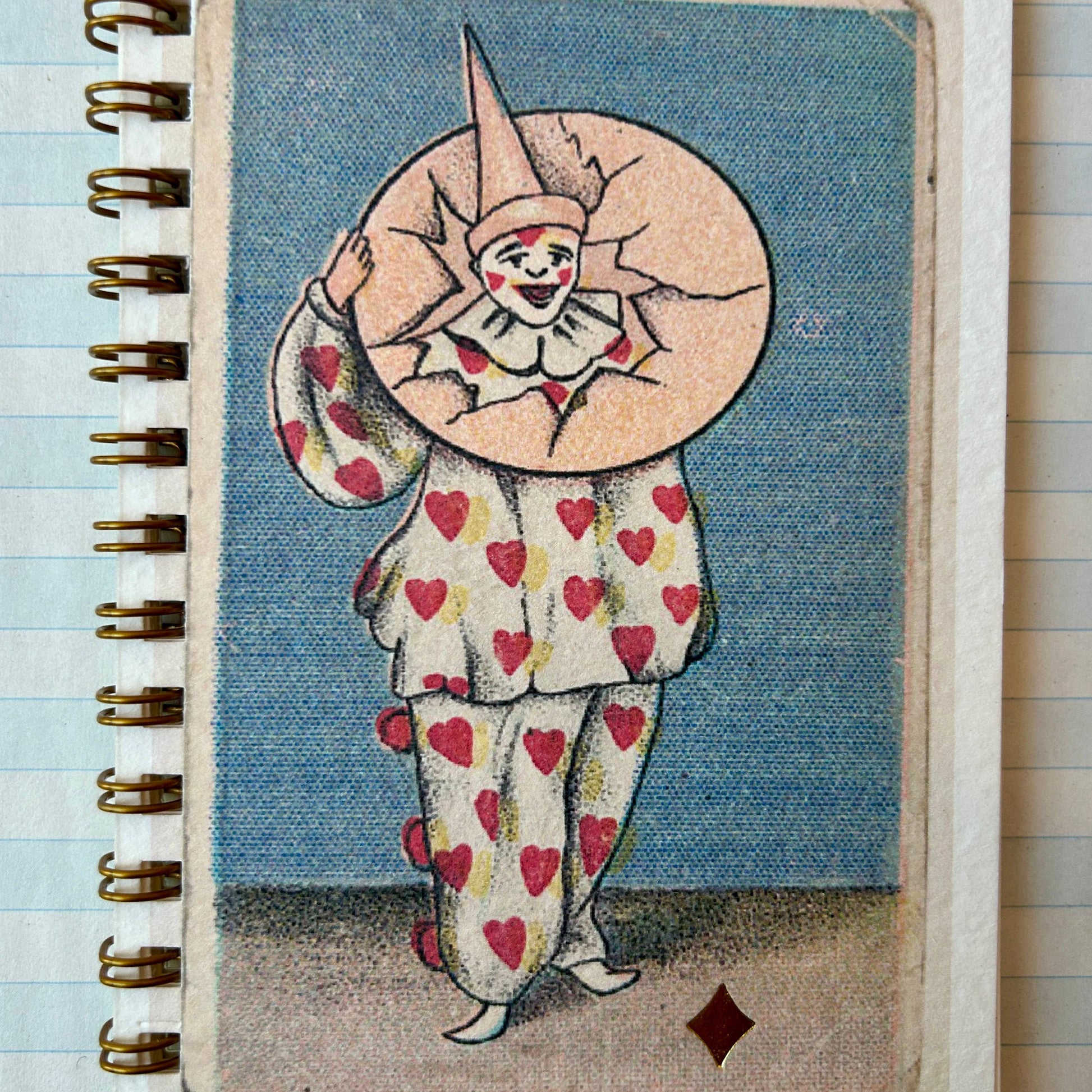 Notebook with a clown design on the cover, featuring hearts and a large head, against a blue background.