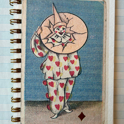 Notebook with a clown design on the cover, featuring hearts and a large head, against a blue background.