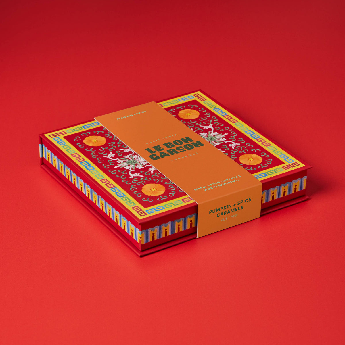 A boxed set of 12 boules de Sargadelós (pumpkin and spice caramels) in a red and orange box with traditional French patterns, set against a solid red background.