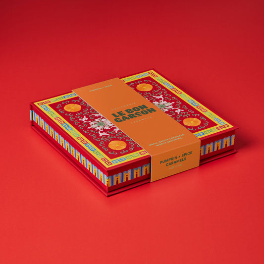 A boxed set of 12 boules de Sargadelós (pumpkin and spice caramels) in a red and orange box with traditional French patterns, set against a solid red background.