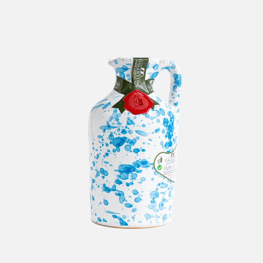 Decorative ceramic jug with blue splatter design and a red label on a white background