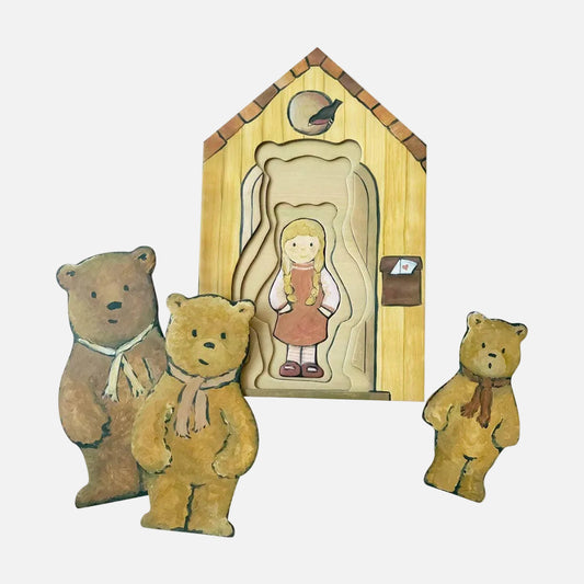 Three teddy bears with a wooden cutout of a girl and a house on a white background