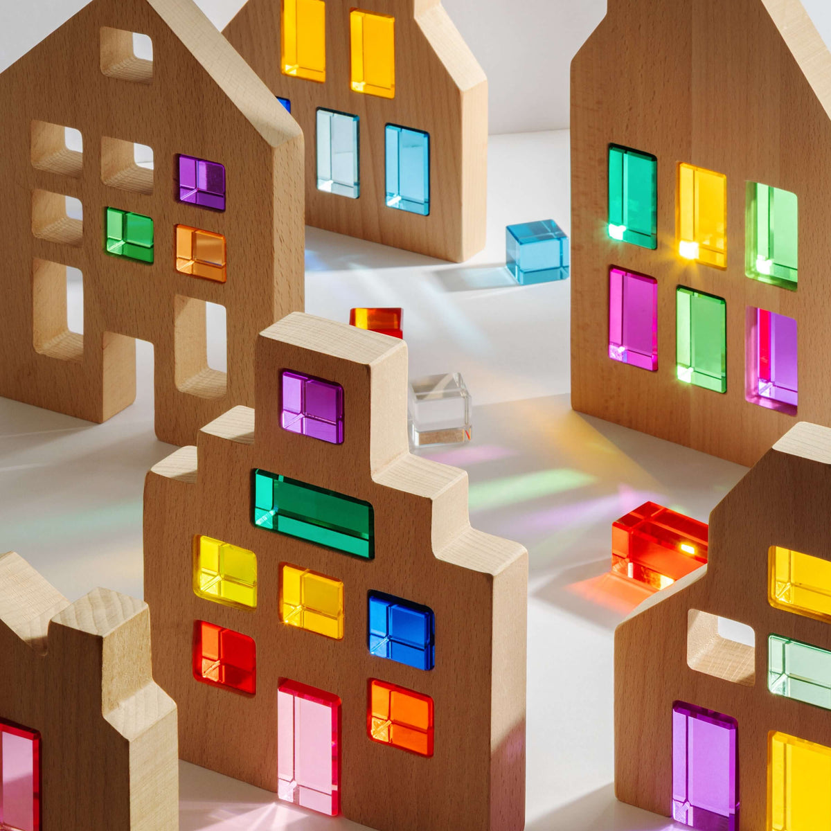 Wooden toy houses with colorful transparent windows on a white background