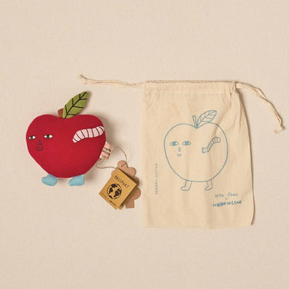 Red apple-shaped toy with a green leaf, a small wooden block, and a beige drawstring bag with an apple illustration on a beige background.