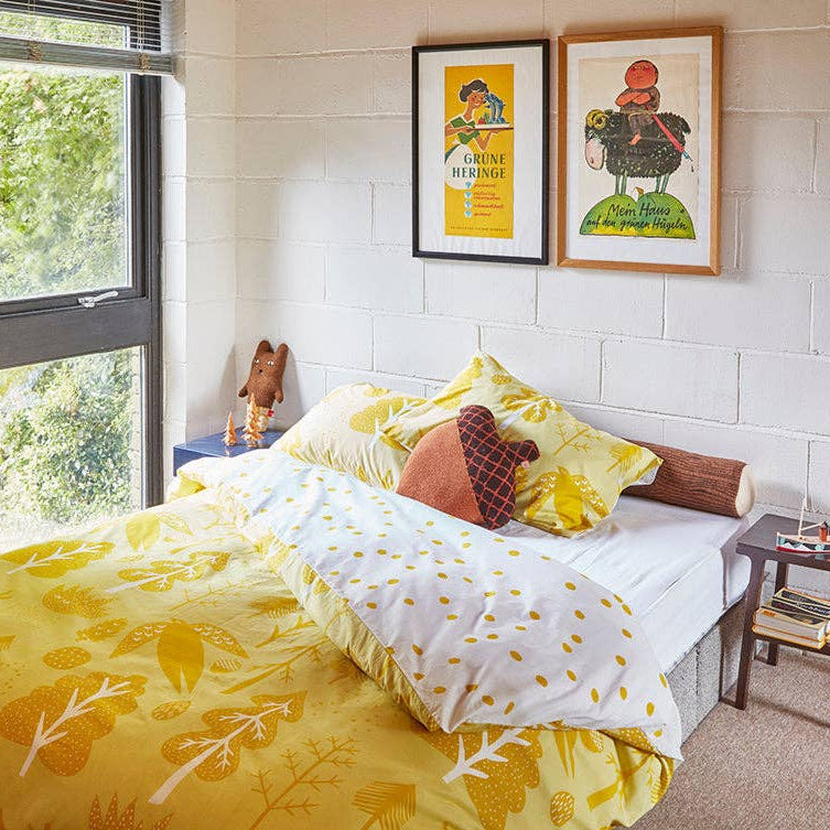Bedroom with yellow floral bedding and framed artwork on the wall.