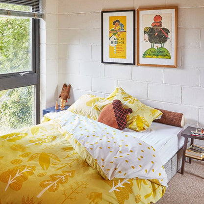 Bedroom with yellow floral bedding and framed artwork on the wall.
