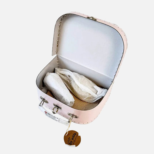 Small pink suitcase with a white interior, containing a white pillow and a brown bag on a white background.