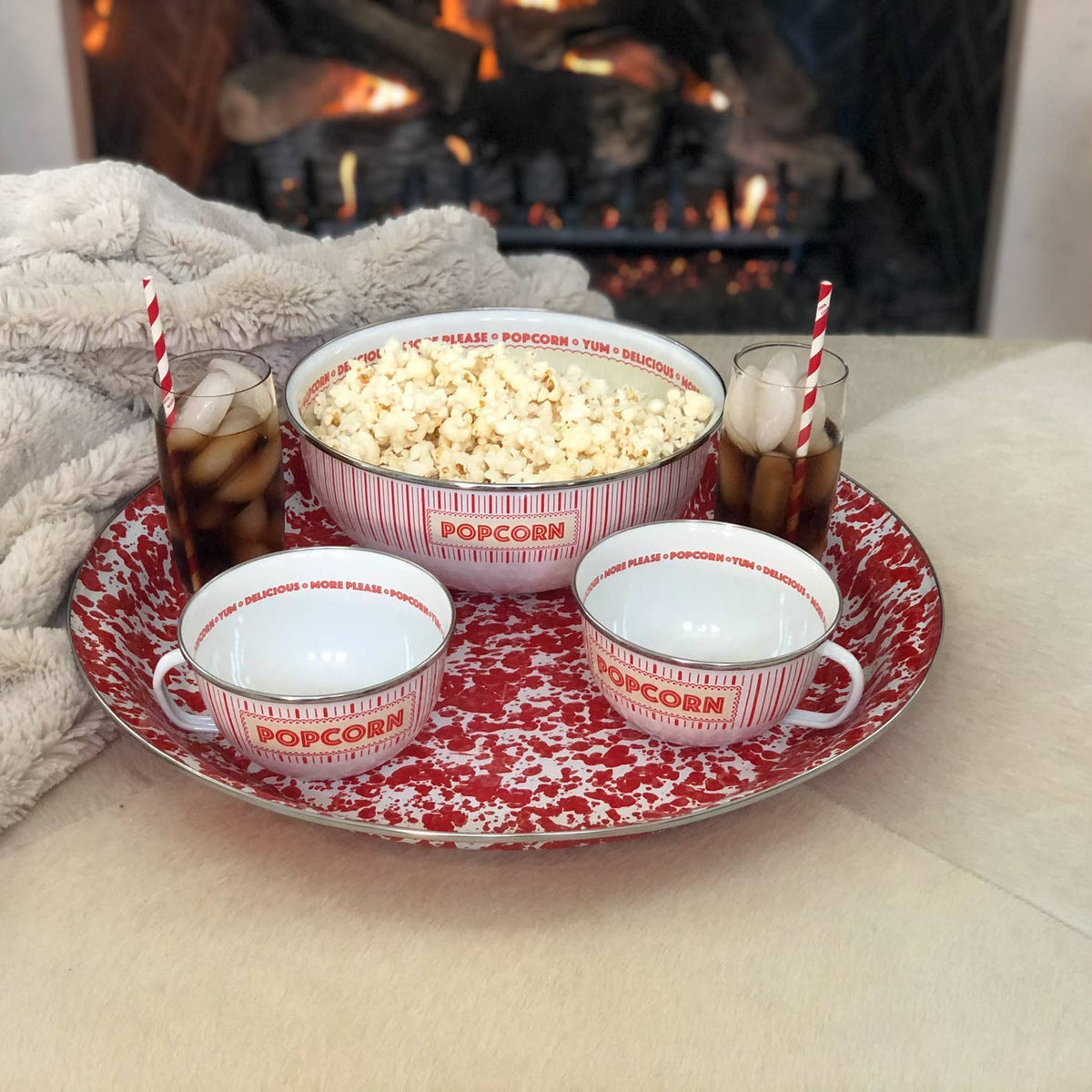 Tray with popcorn, cups, and drinks in front of a fireplace