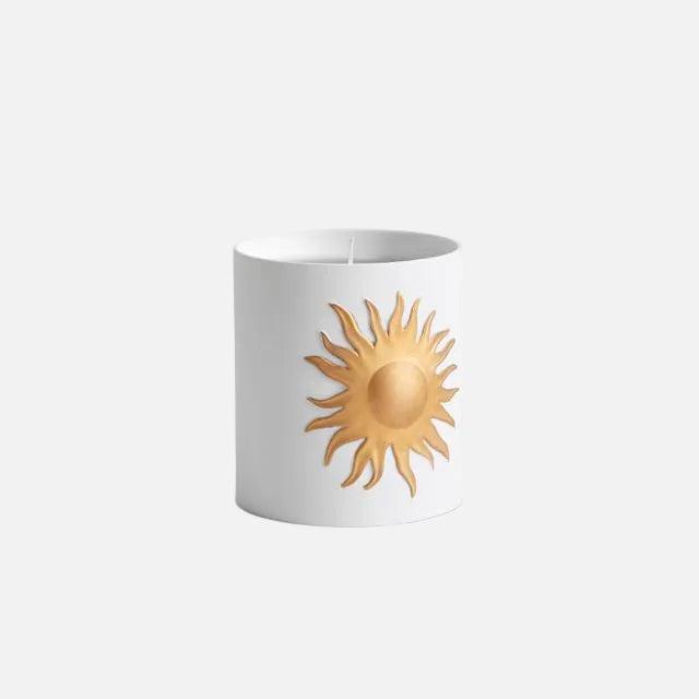 White candle with a gold sun design on a white background