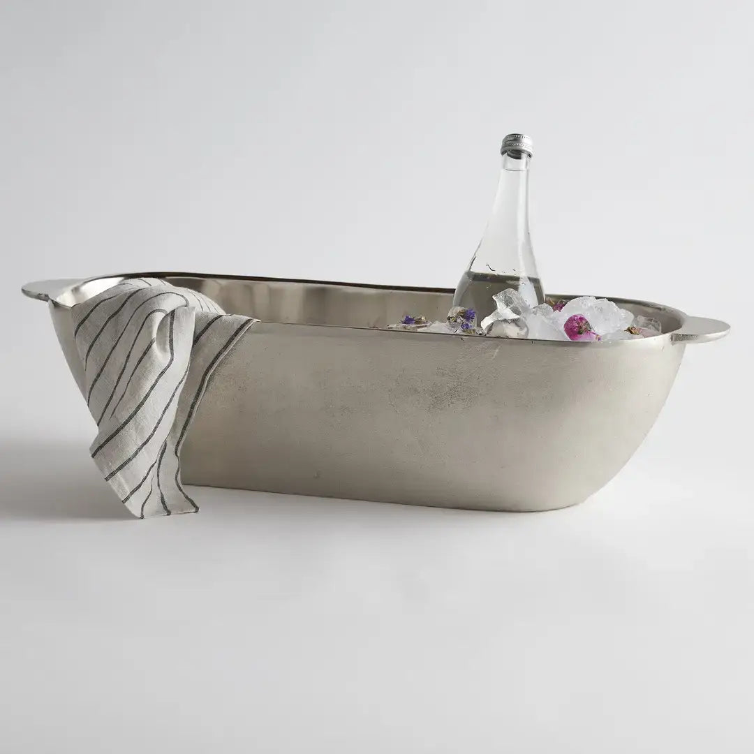 Metallic bathtub with a bottle and towel on a light gray background