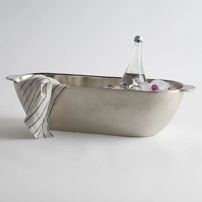 Metallic bathtub with a bottle and towel on a light gray background
