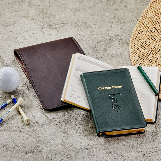 Golf-themed notebook with pen and golf ball on a textured surface