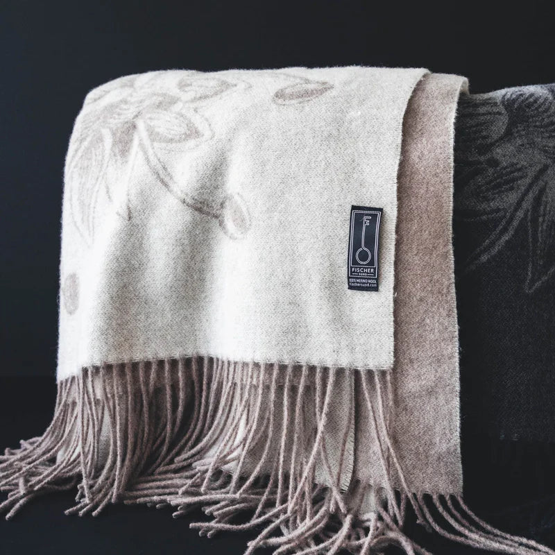 Beige woven blanket with fringe on a dark background