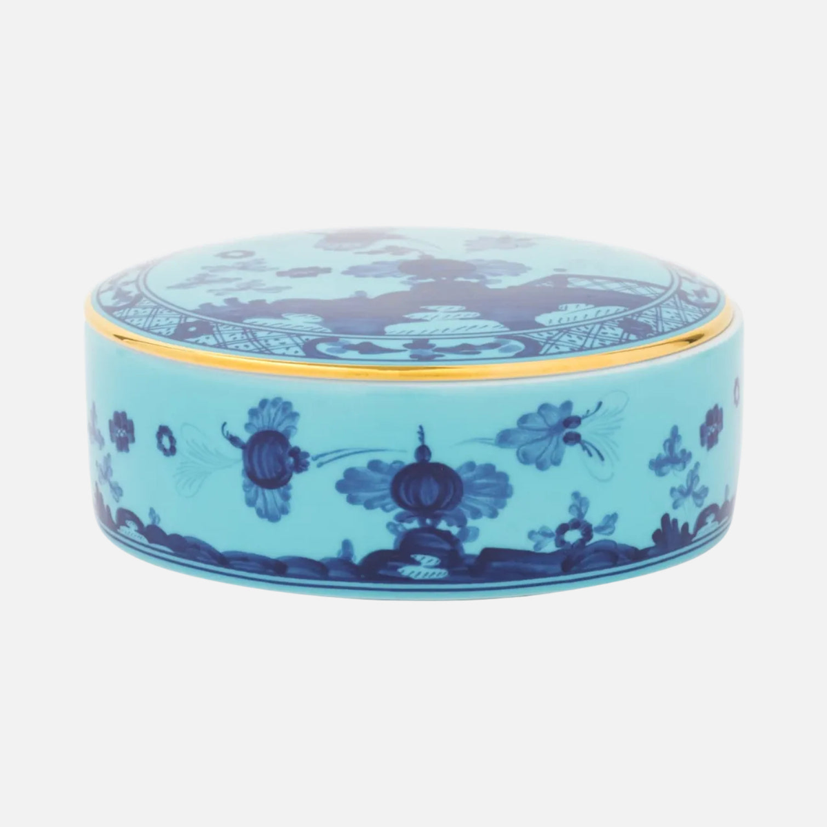 A round porcelain box with cover in Iris, turquoise with hand-painted blue chinoiserie florals and a gold rim.
