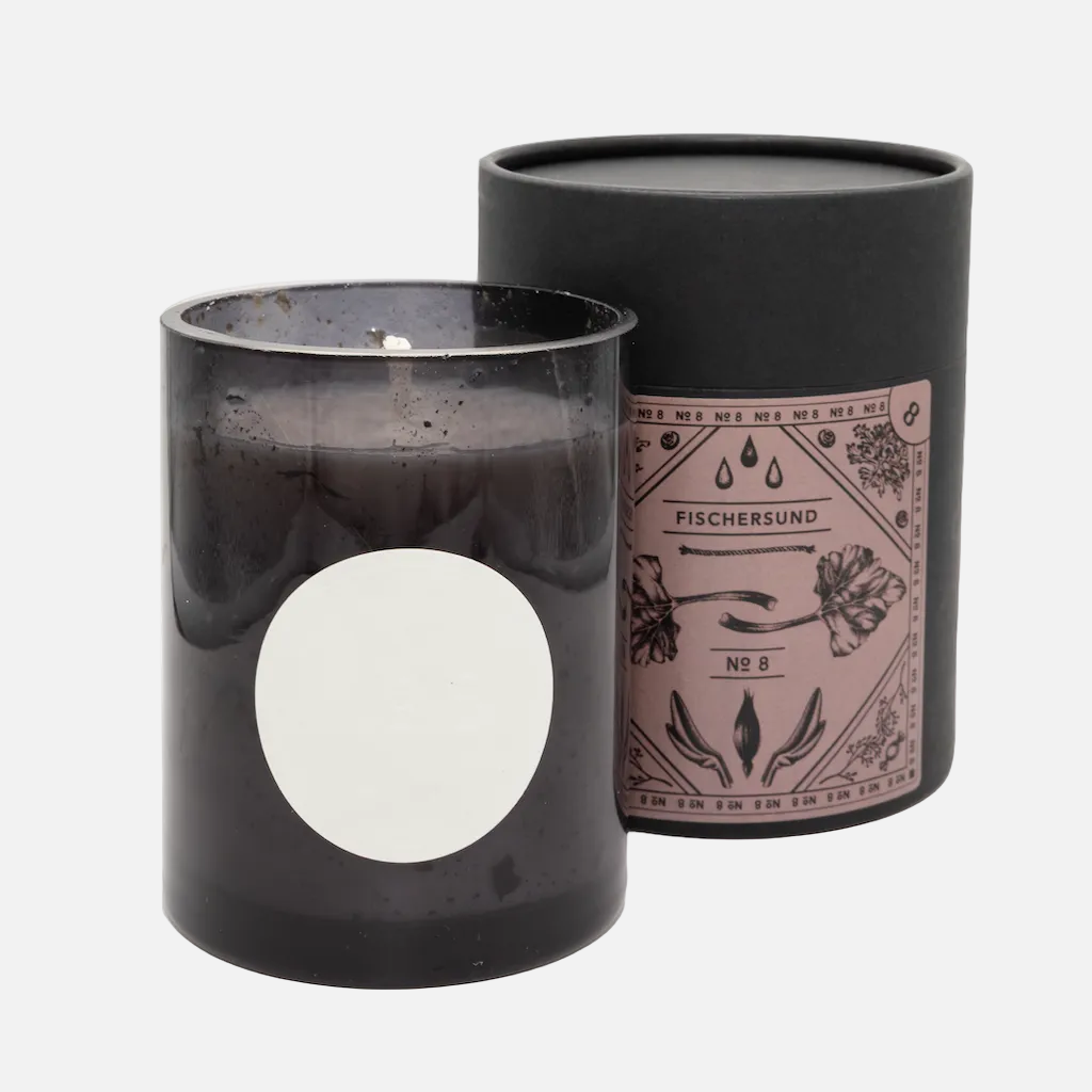 Black candle in a glass container with a decorative label on a white background