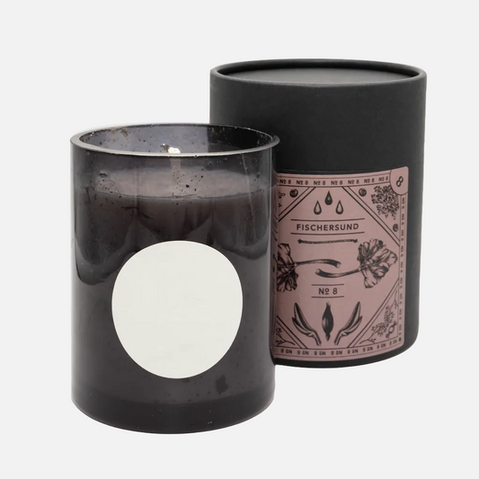 Black candle in a glass container with a decorative label on a white background