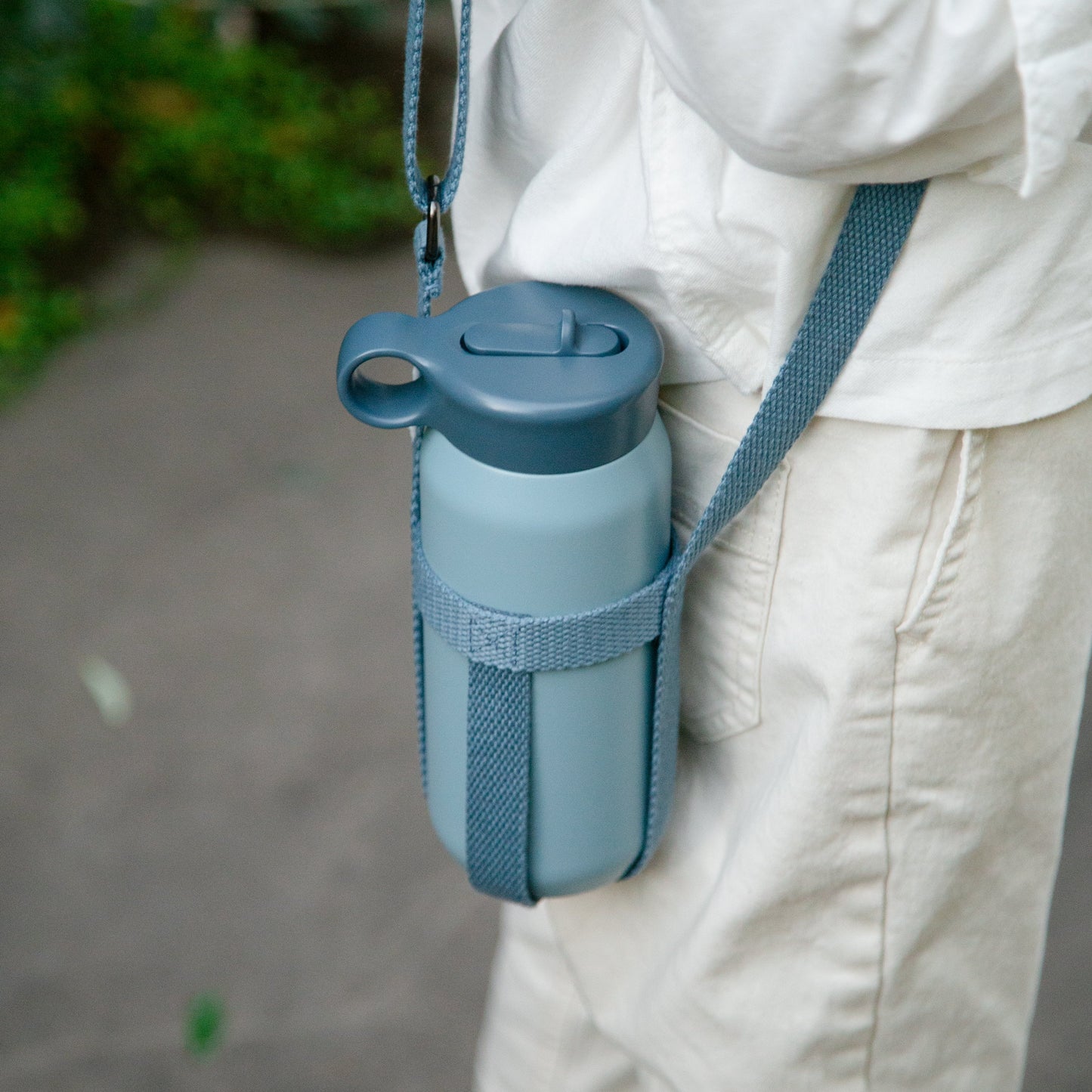 Blue water bottle with holder attached to a person's pants outdoors