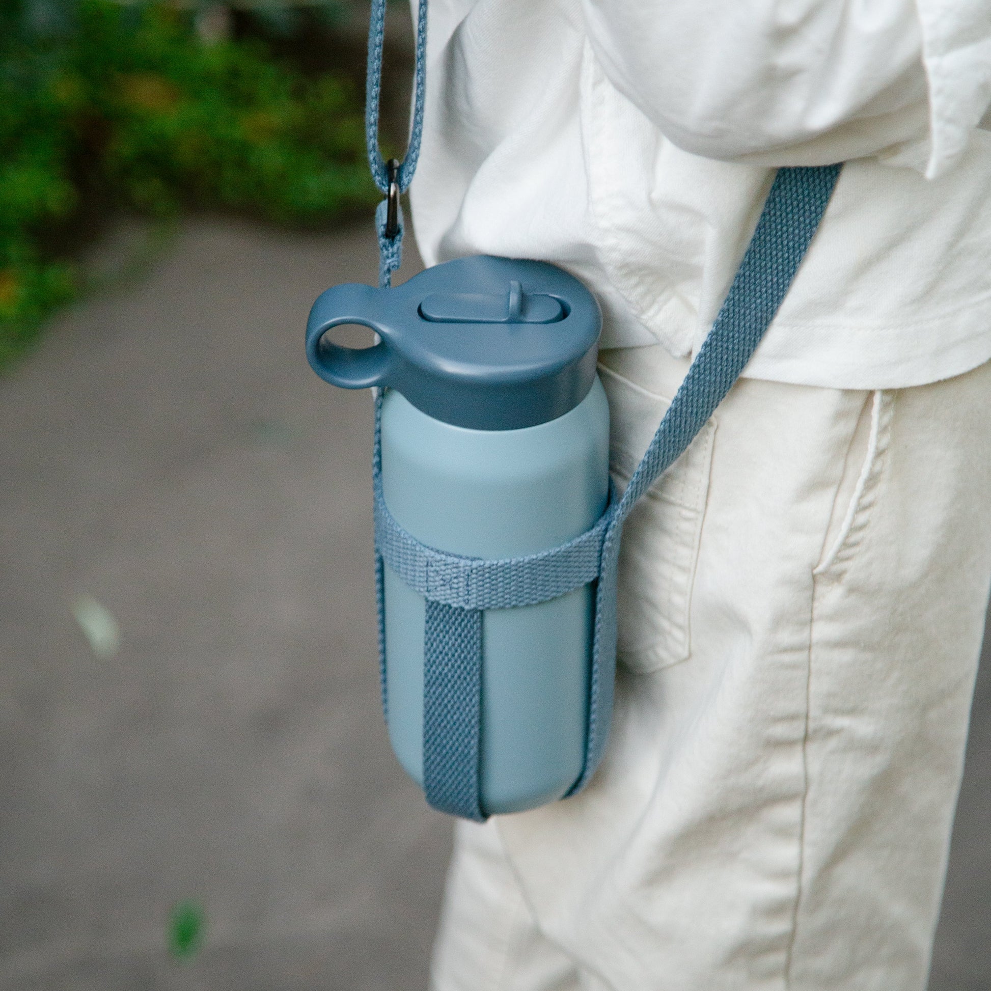Blue water bottle with holder attached to a person's pants outdoors