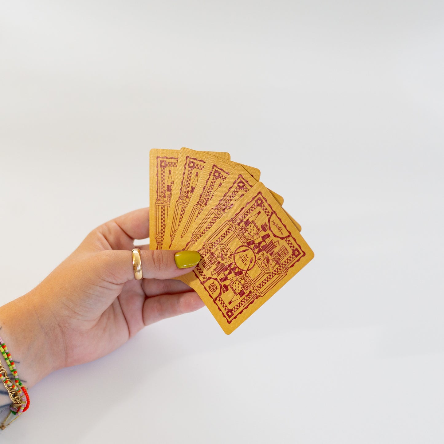 Hand holding four red cards with intricate designs on a white background